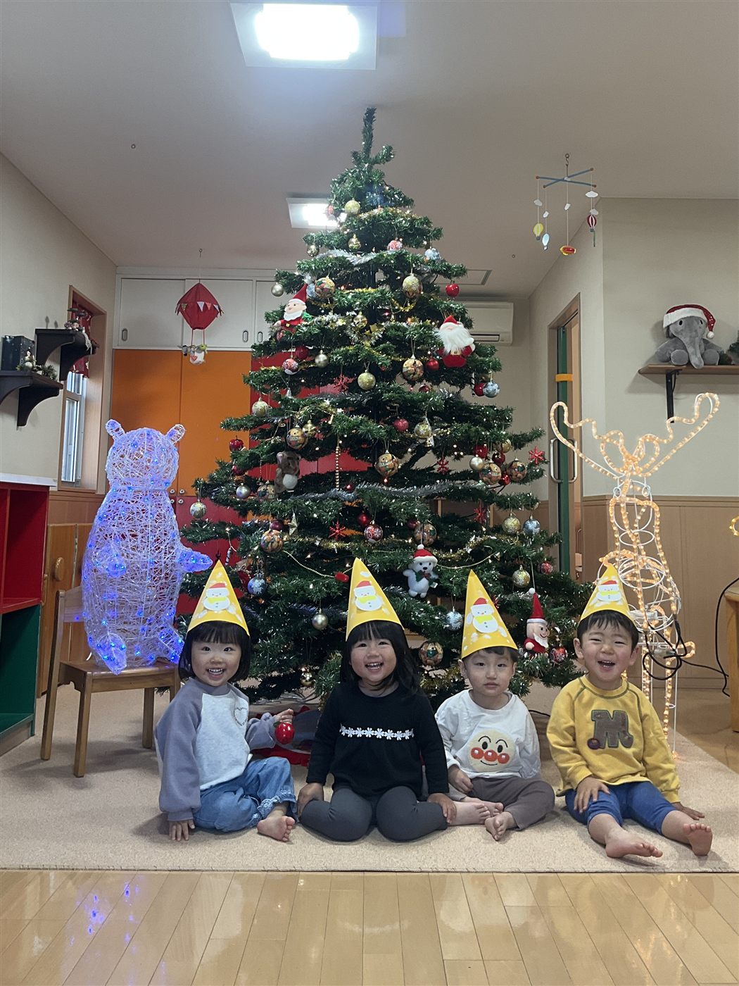 クリスマスツリーの前に座る子どもたち